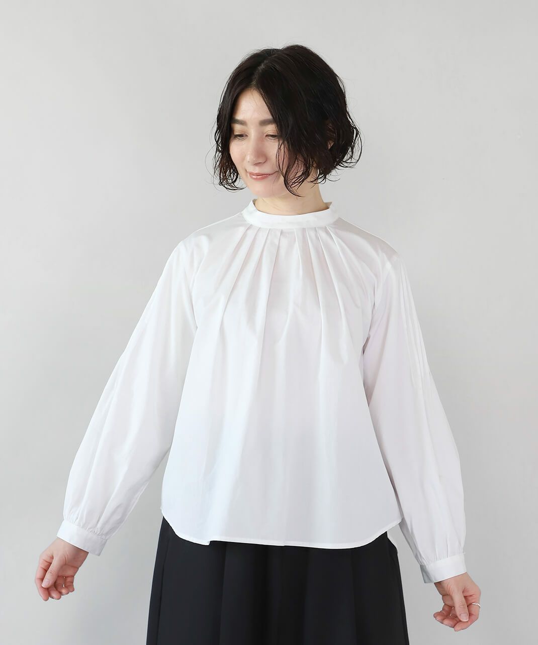 スタンドネックのタックが華やかな印象