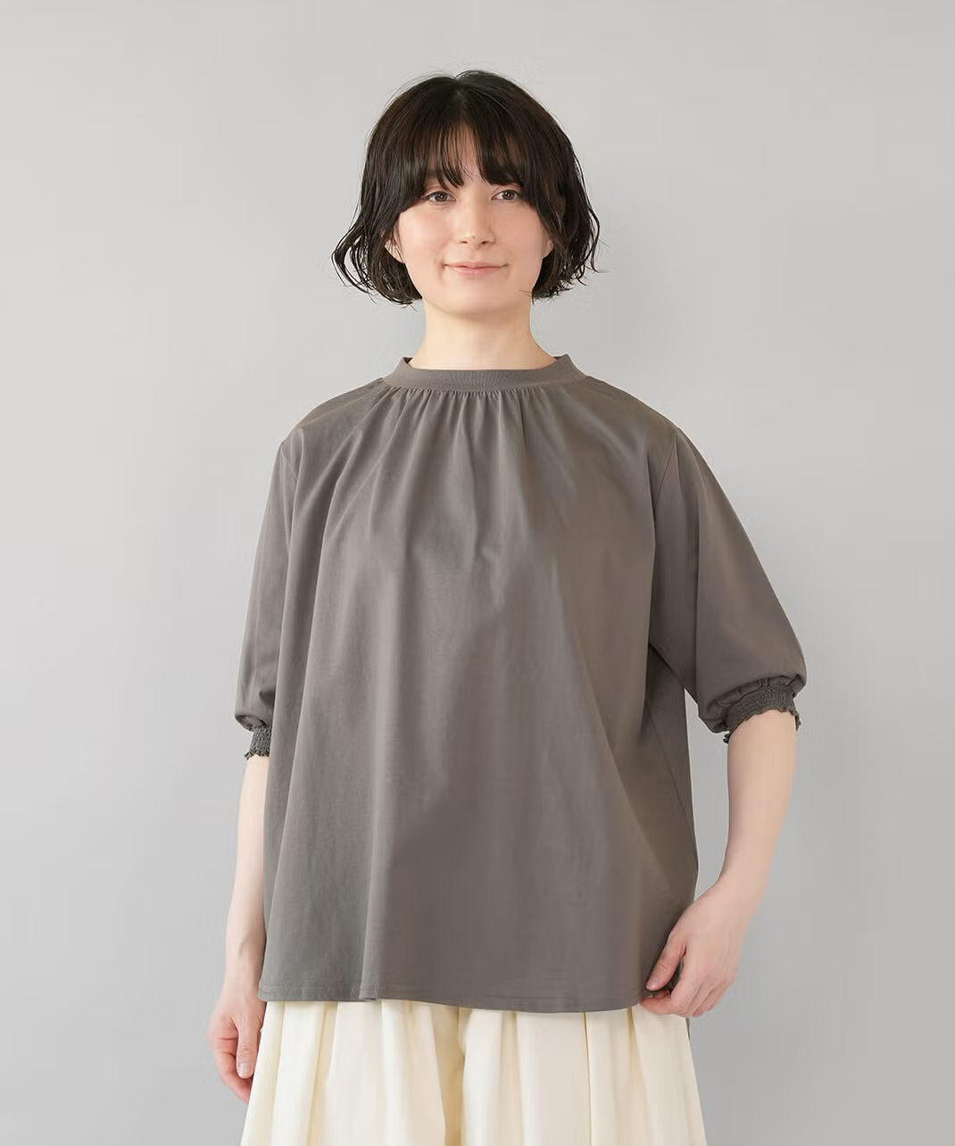 首元のギャザーでふんわりと広がるシルエット